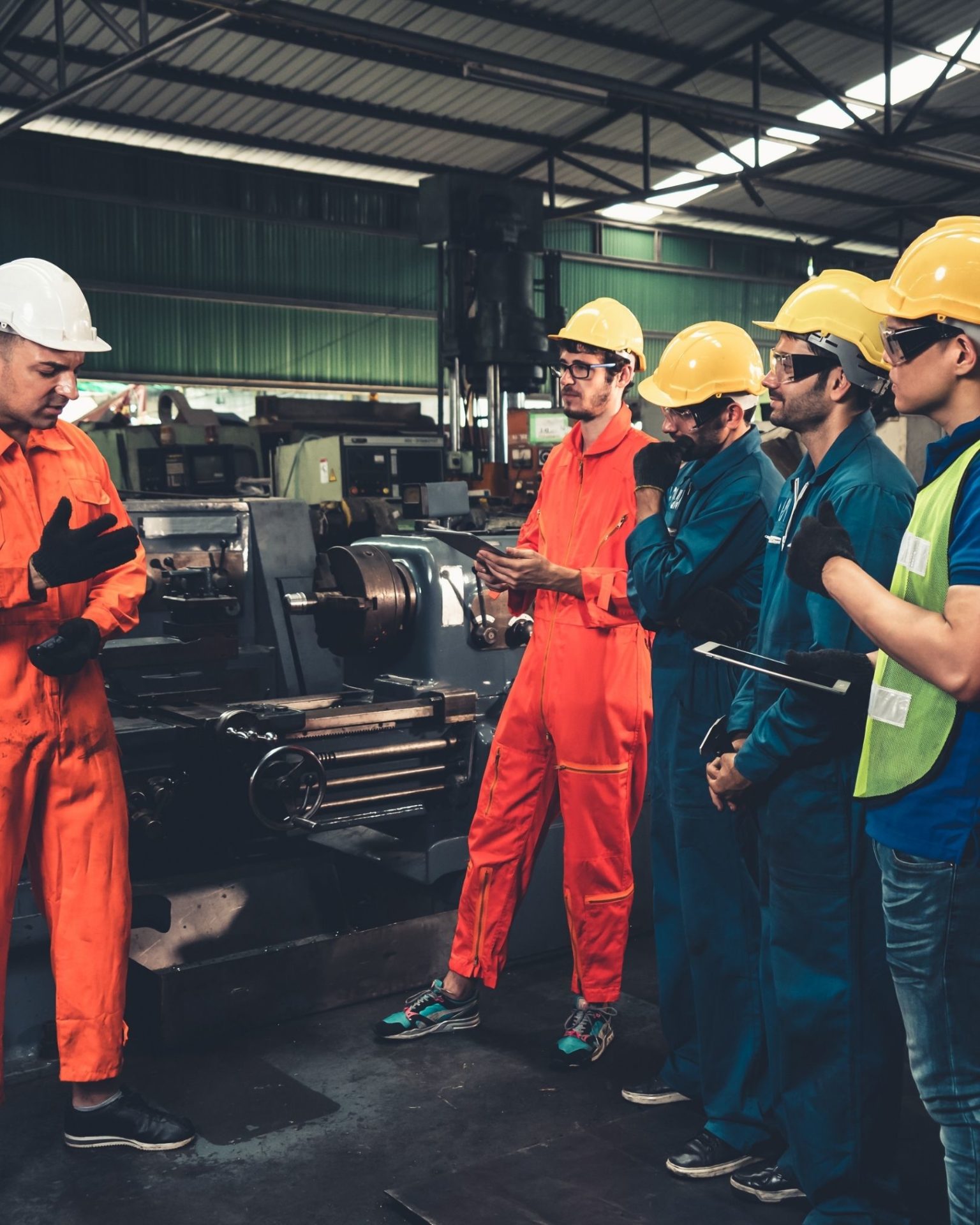 Dos trabajadores industriales con equipo de seguridad examinan maquinaria pesada