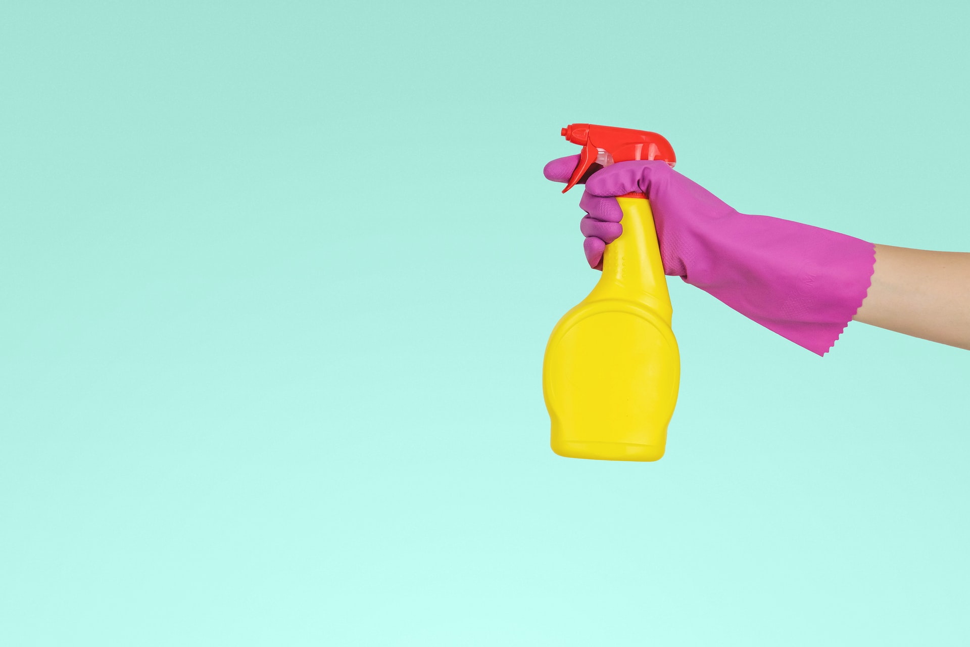 jeshoots-com-__ZMnefoI3k-unsplash (1) mano enguantada con botella de limpieza