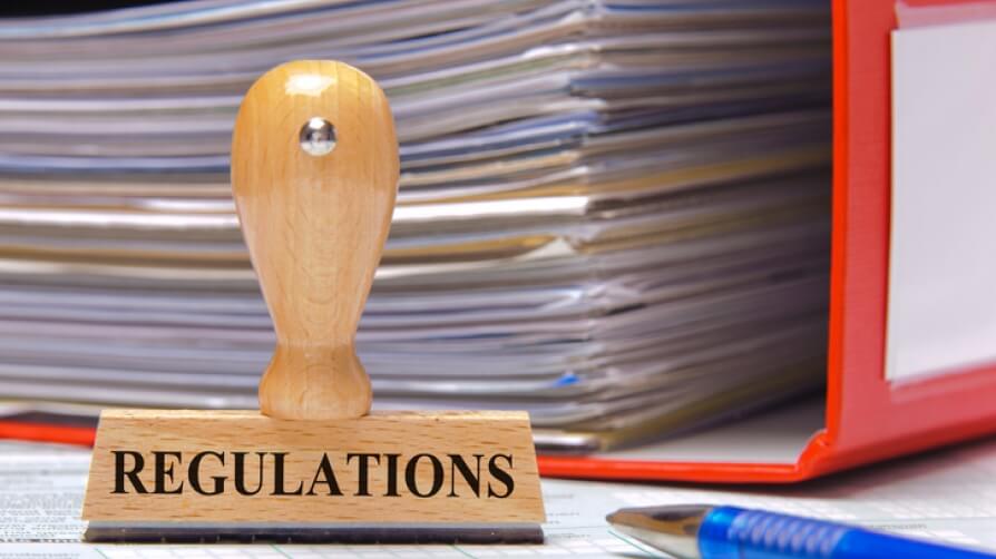 stamp with the words regulations in front of a book of regulations