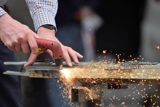 Laser cutting of flat sheet metal steel material with sparks die grinder blue and white shirt guy